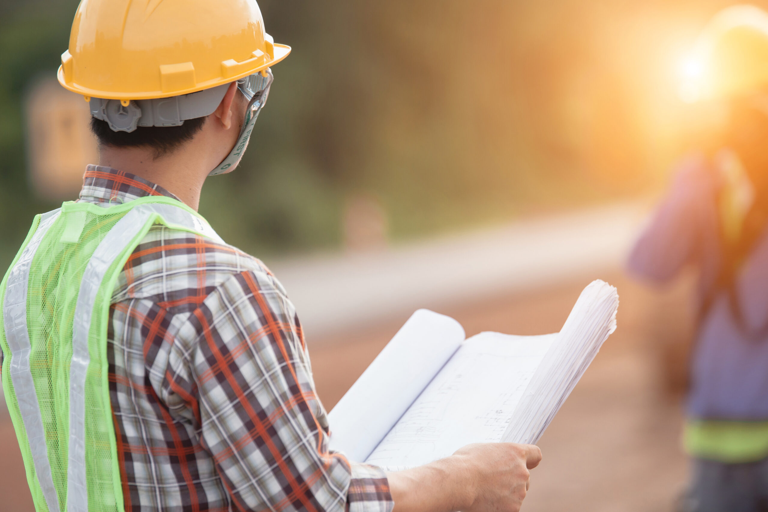 Architect holding rolled up blueprints at construction site